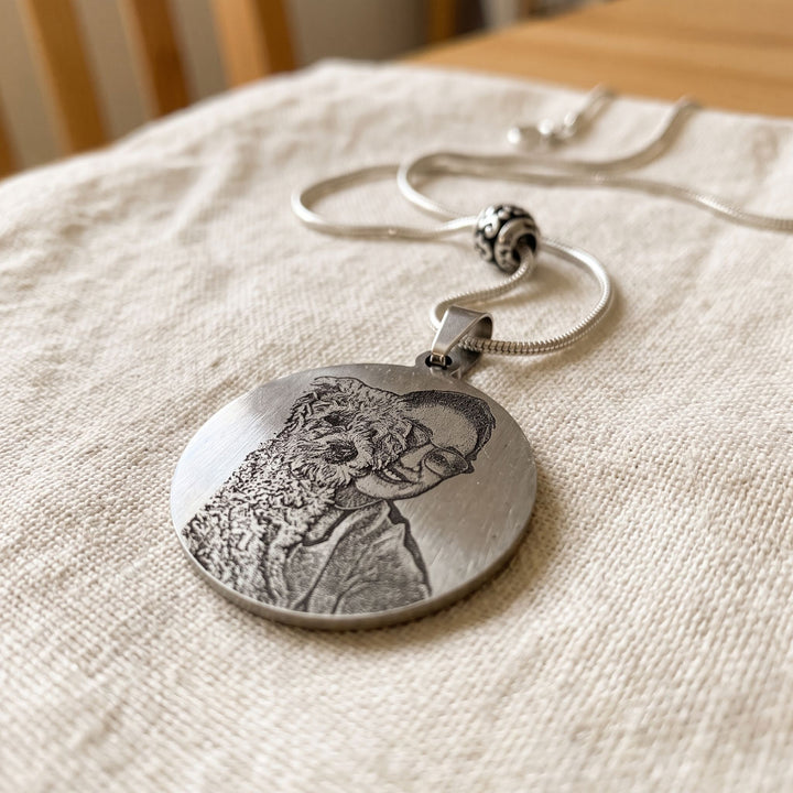 round pet photo necklace with an engraved pet portrait, close-up of the engraving