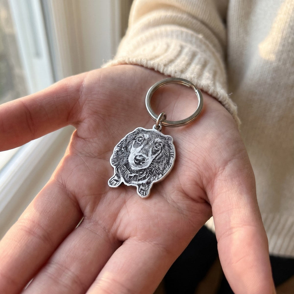 Engraved silver dachshund keychain resting in an open palm