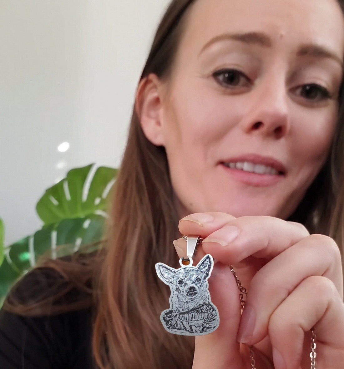 Woman holding up her engraved chihuahua photo necklace to the camera