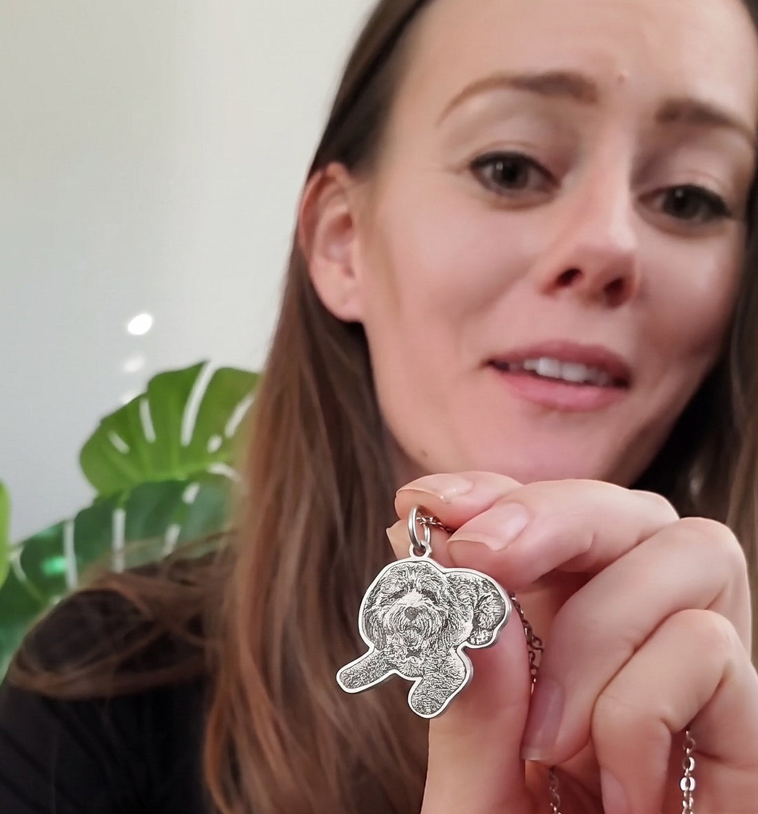 Woman holding up her engraved doodle photo pendant to the camera