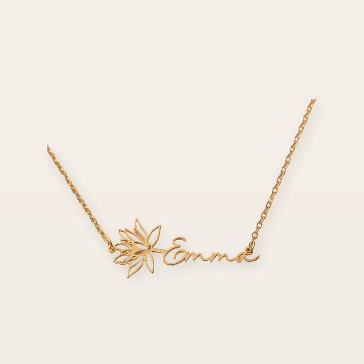 Birth flower name necklace, gold tone, on a plain background