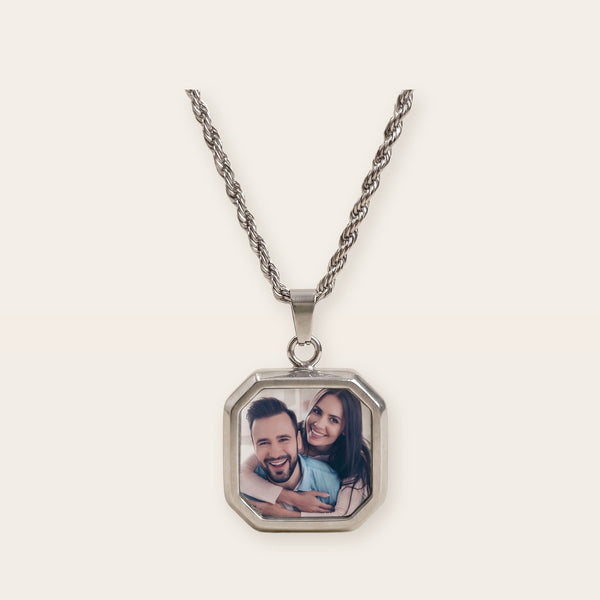 Heat activated photo necklace, silver tone, on a plain background