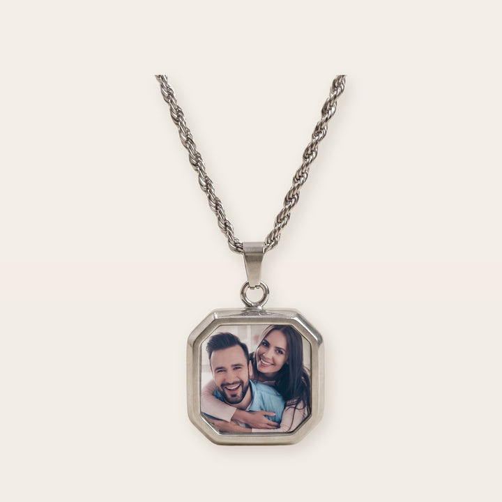 Heat activated photo necklace, silver tone, on a plain background
