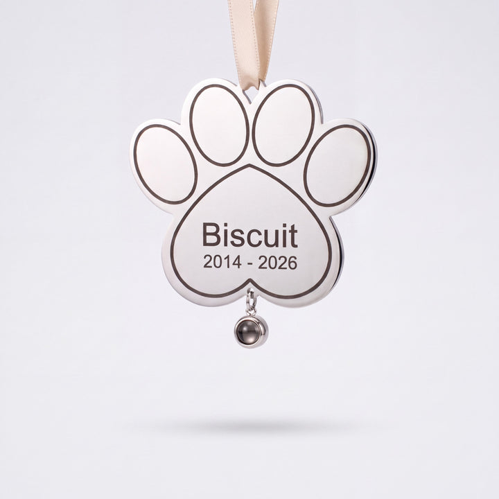 Silver paw print pet memorial ornament engraved with a pet name and years, photo stone hanging below