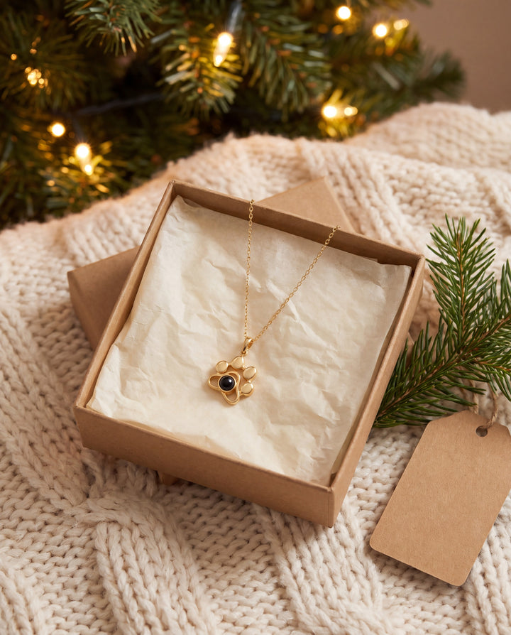 Gold paw projection necklace in a gift box under a Christmas tree