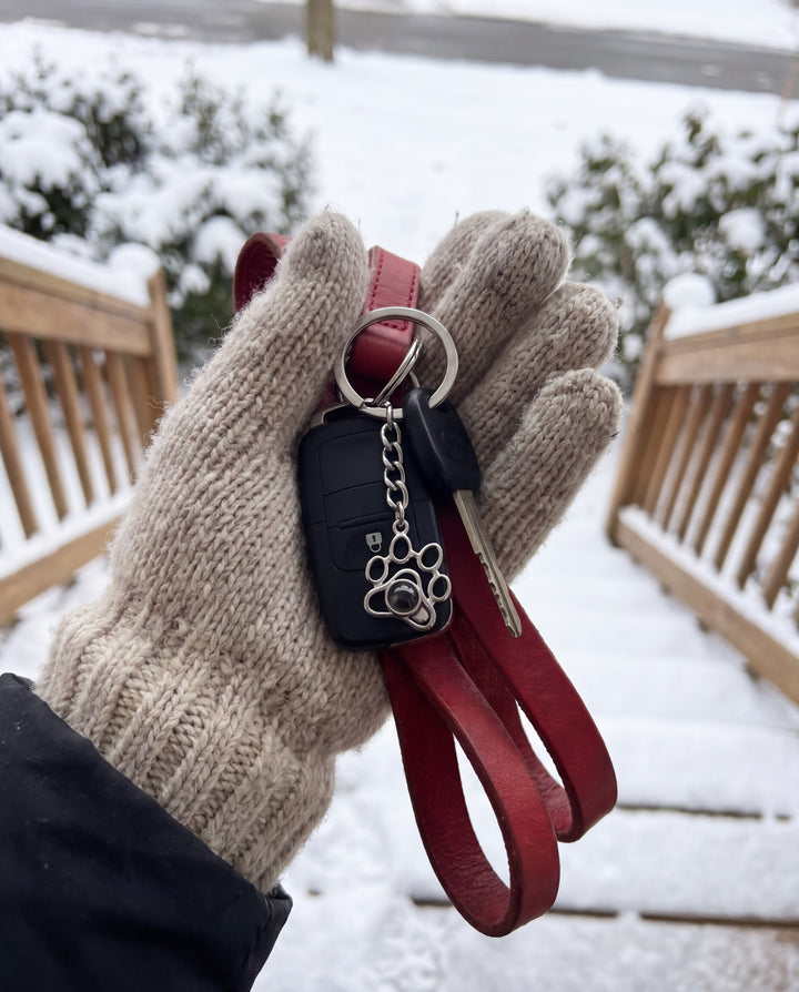 Paw projection keychain on car keys held in a winter glove with a dog leash