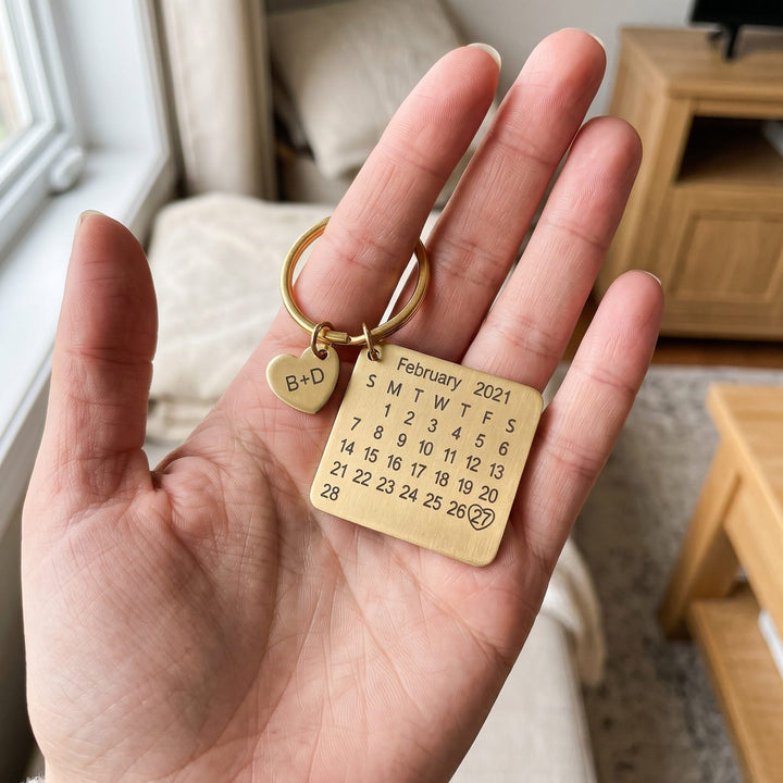 personalized calendar keychain with an engraved date, held in a hand to show true size