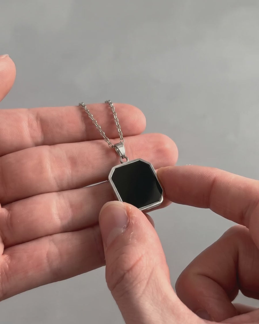 Silver heat-activated photo necklace warmed by a thumb to reveal the photo